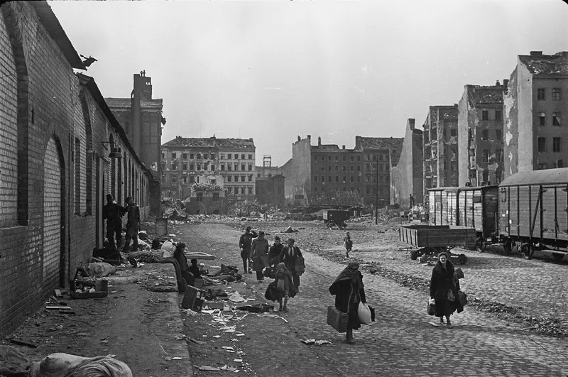 Civilians carrying their belongings pass along a street in ruined Berlin following the surrender of the city