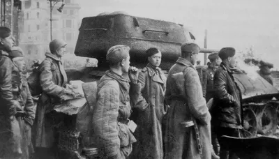 Red Army soldiers and officers waiting by a wrecked T-34-85 tank in front of the Moltkebrücke bridge in Berlin