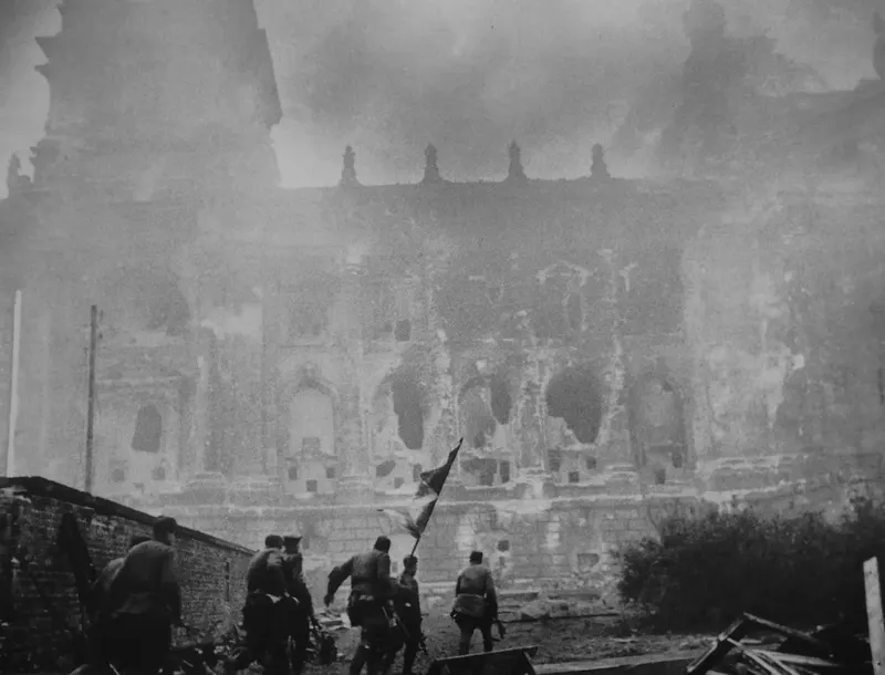 A Soviet assault group with a banner moves to the Reichstag