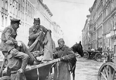 Soviet orderlies move an injured soldier from a stretcher to a wagon