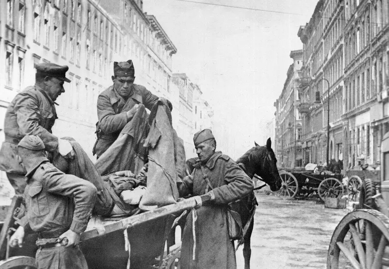 Soviet orderlies move an injured soldier from a stretcher to a wagon