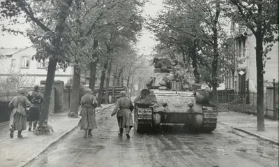 Red Army troops advance into Berlin's suburbs alongside a Soviet tank